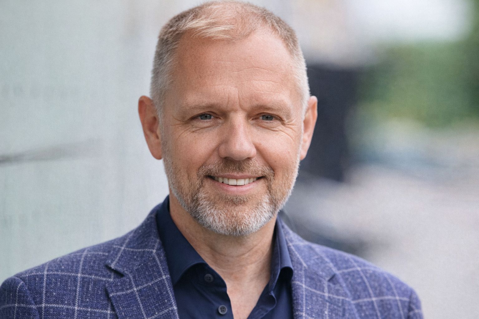 Närbild på en medelålders man med kortklippt, tunt ljust hår och ett leende.