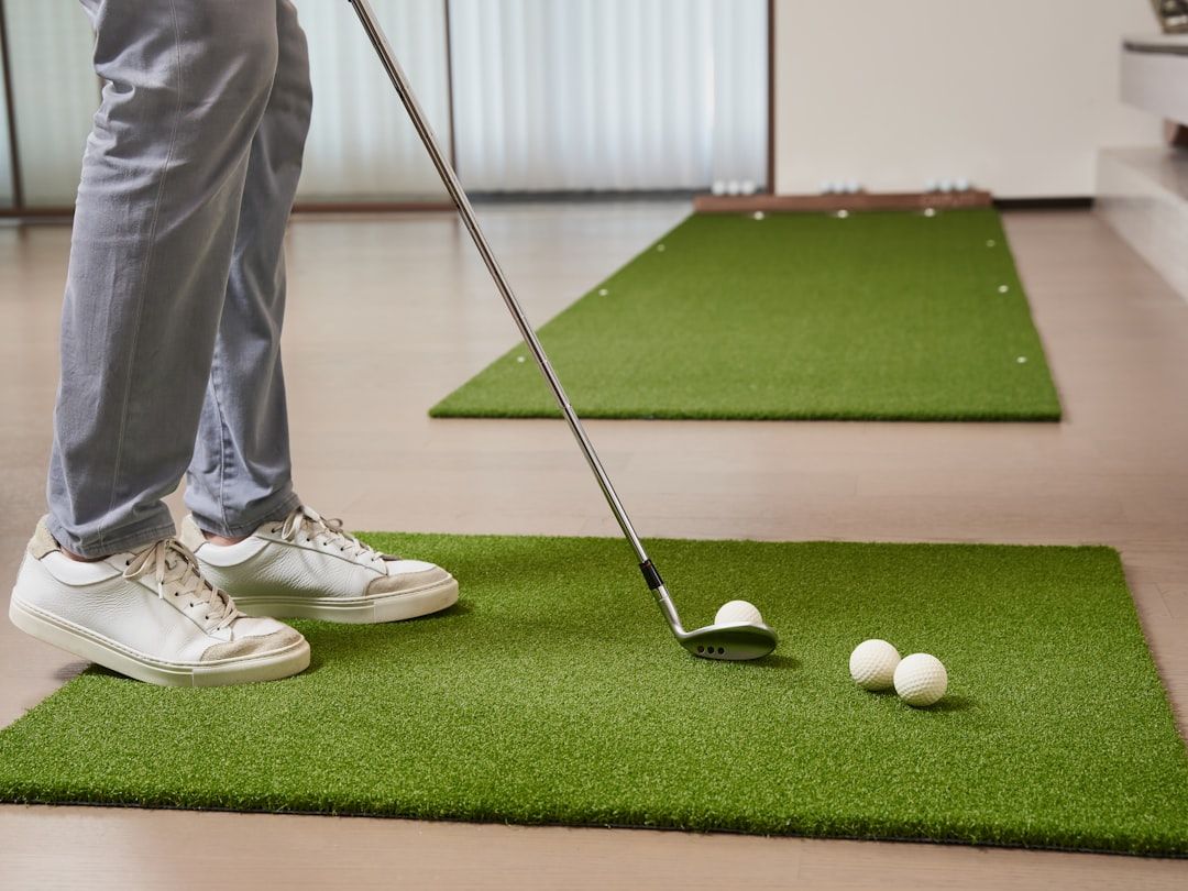 En person som tränar golf inomhus på en konstgräsmatta.