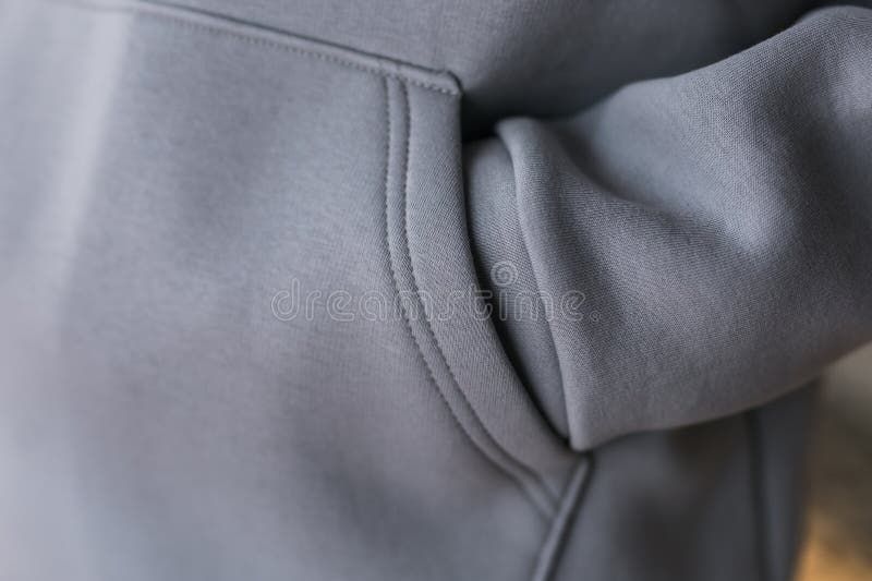 Närbild på tyget och fickan på en grå hoodie.